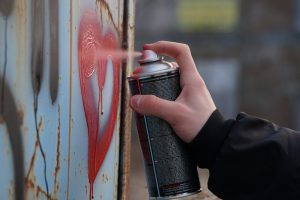 person holding black and red spray can